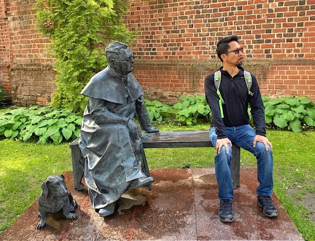 Sculpture on a bench with dog outside a basilica in Kaunas Lithuania