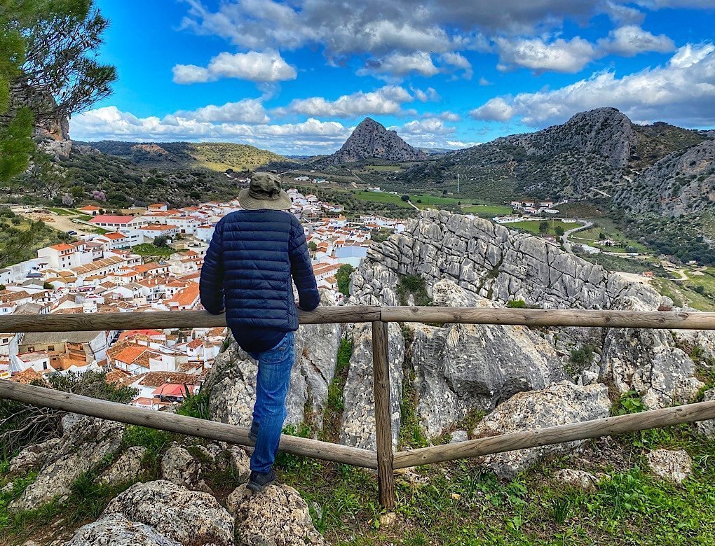 Trin standing at a viewpoint over the town of Montejaque, Spain. Limestone mountains point to the sky around it.