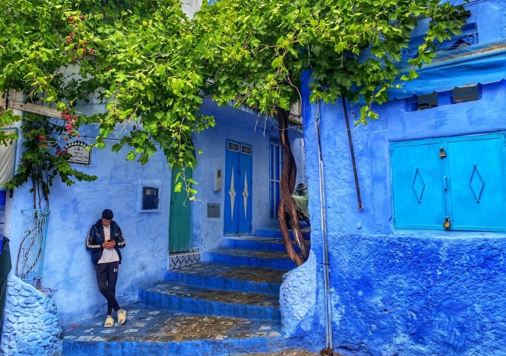 Local on his phone standing on the steps of a street in Chefchaouen the blue pearl