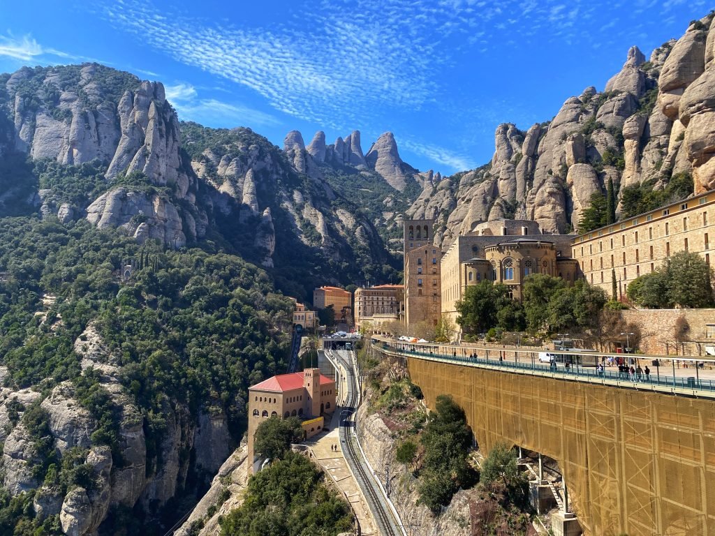 Montserrat  monastery clings to a cliff on the side of serrated mountains.