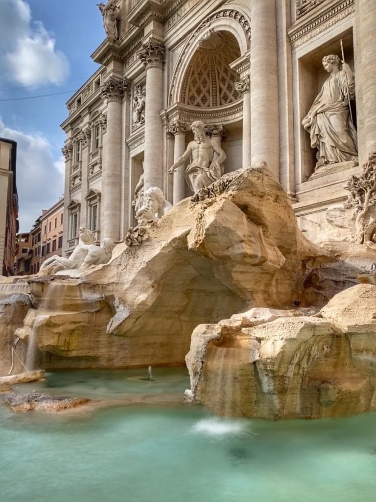 Monuments above Trevi Fountain and blue water beneath