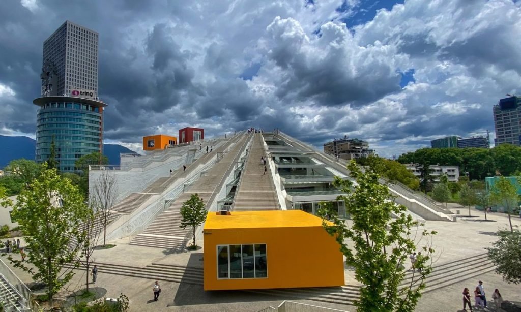 The transformed Pyramid of Tirana with a yellow office space beside it.