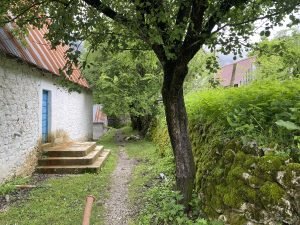 Blue door on a home in Theth. A walking path extends beside it and an old stone wall