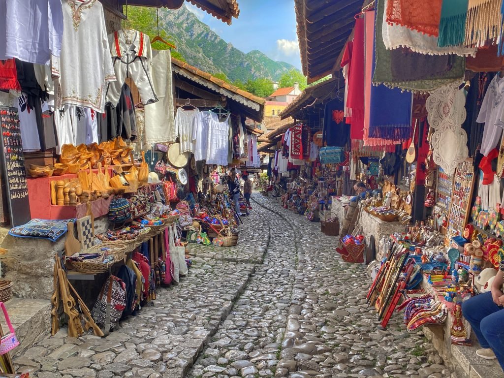 Rounded stones pave the narrow path through the old Bazaar in Krujë. Colorful handmade items fill the walls of the shops lining the pathway.