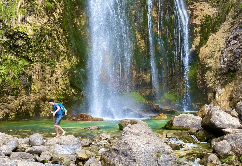 Peter crossing the stream with the waterfall behind him.