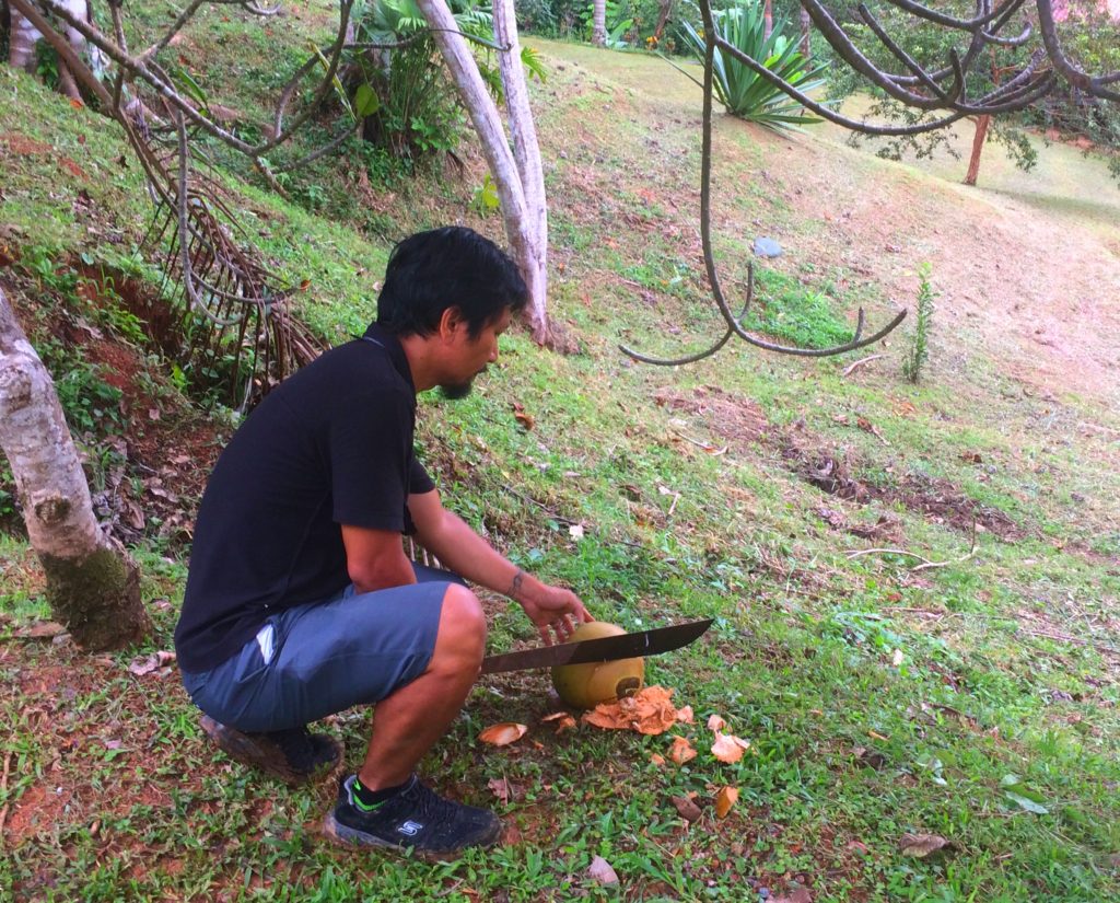 Trin opening a coconut with his machete