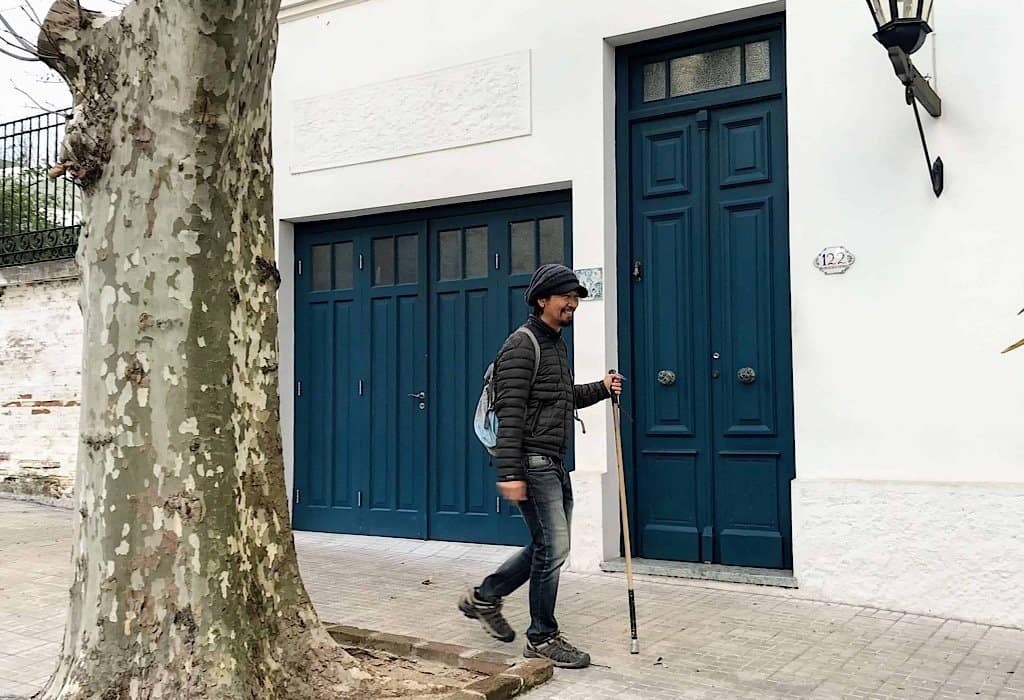 Trin walking by a blue door in Uruguay