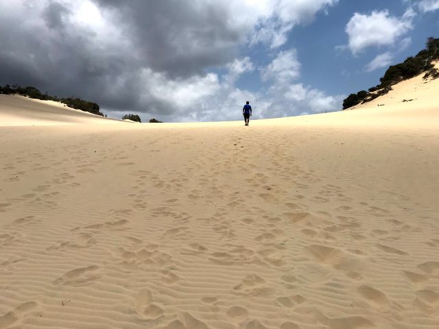 Trin walking to the top of a sand dune in the Great Sandy National Park