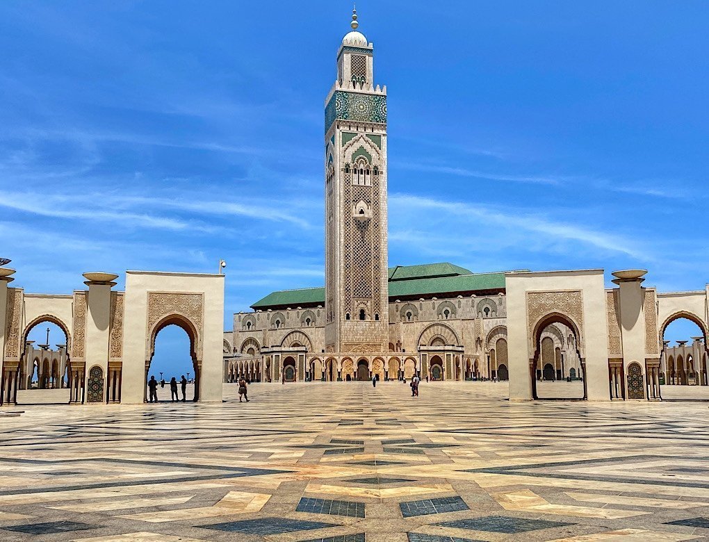 The tower of the Hassan II Mosque looms over the massive tiled square leading up to it.