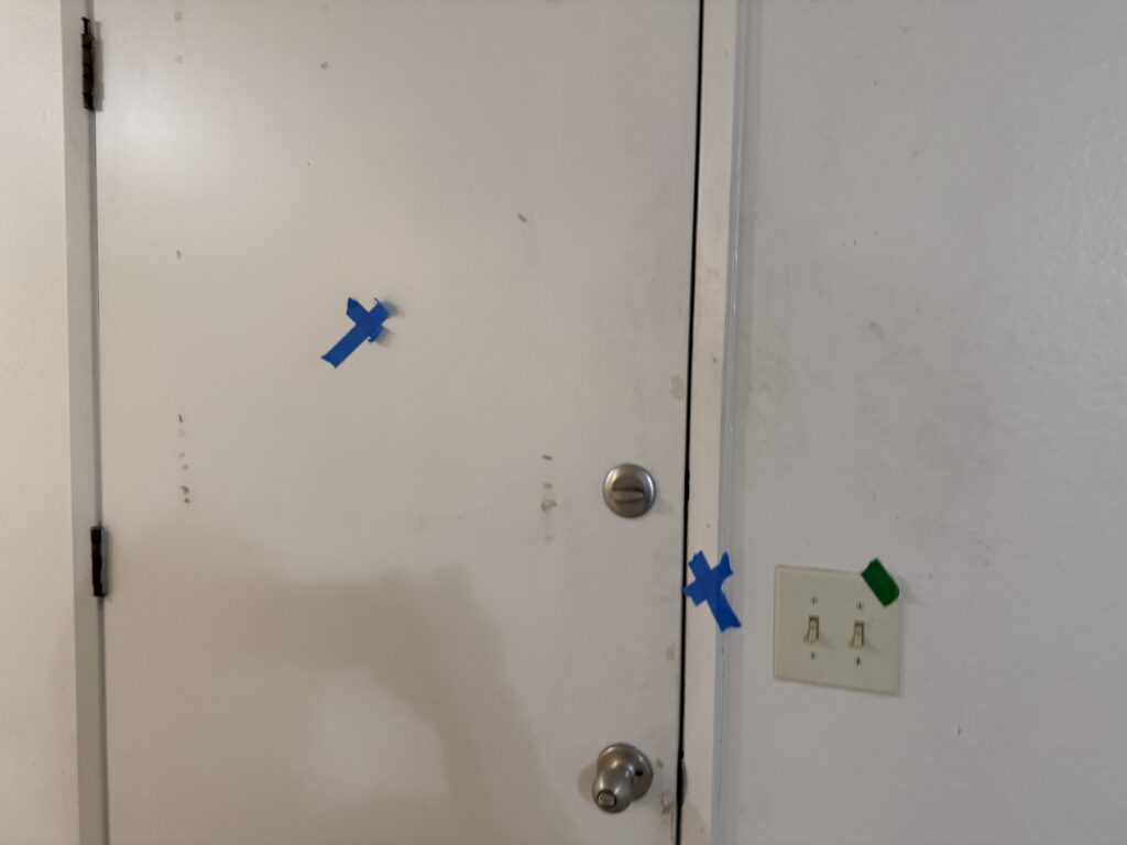 Inside the front door. Grim on the walls, scratches in the paint, broken light switches.