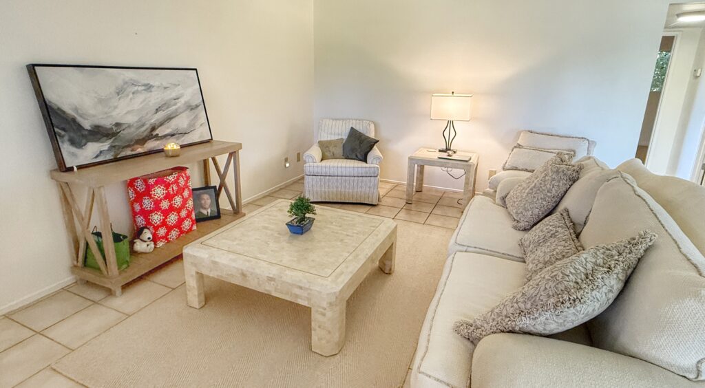 Living room with white couch, two chairs, coffee table, and area rug.