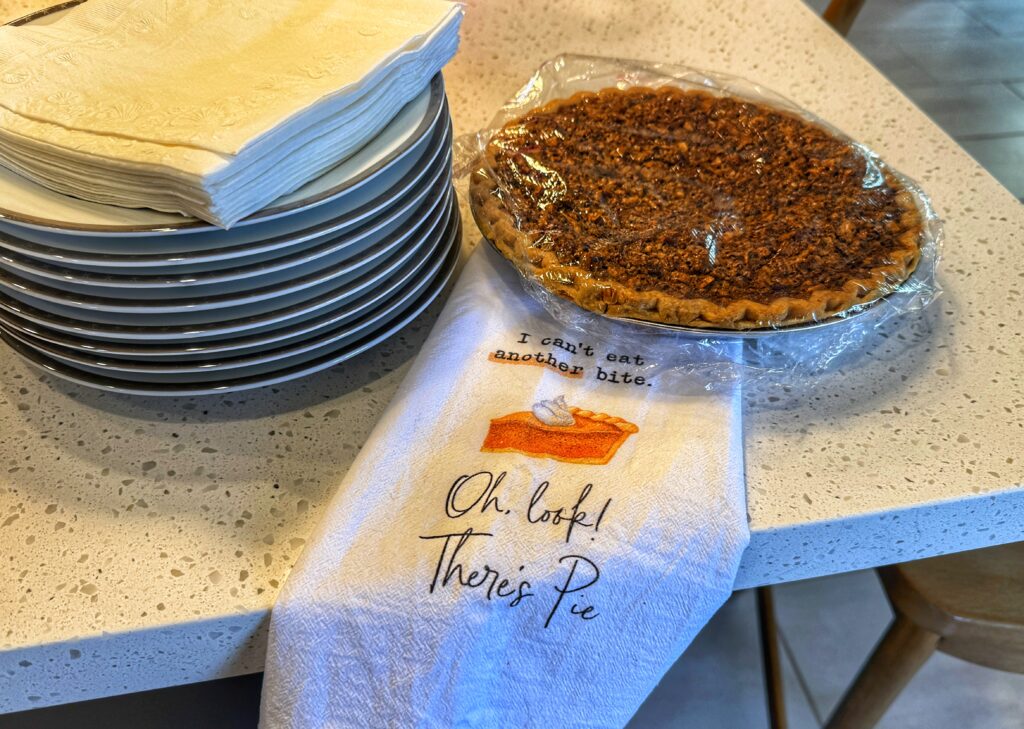 Pecan pie with a towel that reads "I can't eat another bite. Oh. Look! There's Pie