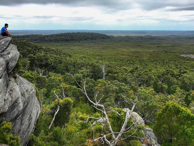 Trin sitting on the edge of Mount Chudalup looking out over the plain